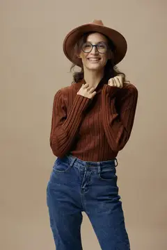 Улыбчивая девушка в шляпе и очках на бежевом фоне