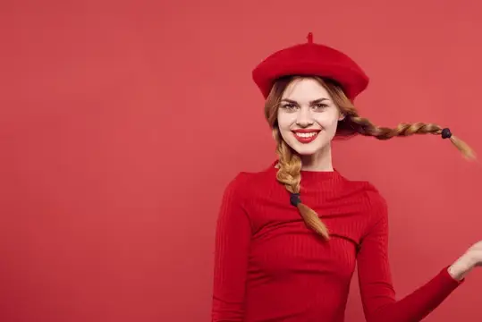 Улыбчивая девушка с рыжими косами в красном берете на красном фоне