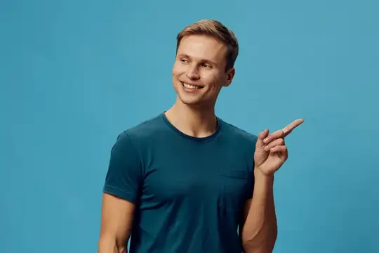 Улыбающийся светловолосый парень в футболке указывает пальцем в сторону на синем фоне