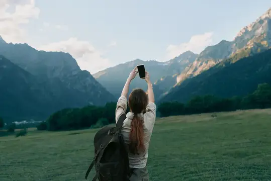 Активная женщина исследует природу, фотограф в повседневной одежде на фоне гор и луга, солнечный свет и ветерок, подчеркивающие образ жизни, свободу, исследования и приключения на свежем воздухе…