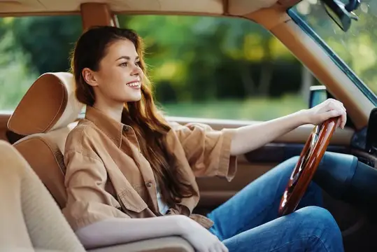 Улыбающаяся темноволосая девушка за рулём автомобиля