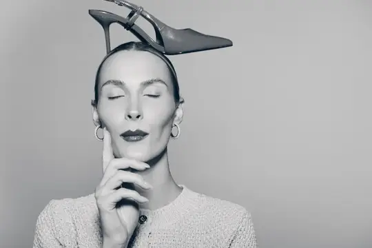 Портрет бледной белой женщины с закрытыми глазами, балансирующей туфлёй на высоком каблуке на голове и касающейся лица
