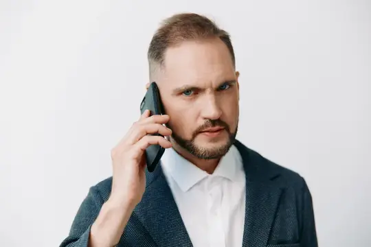 Субъект использует телефон, чтобы передать активную работу, со спокойным, но уверенным выражением лица, изображая срочность, ясность и контроль в корпоративной обстановке