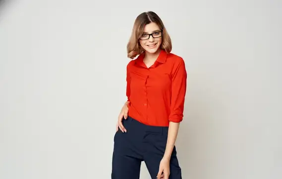 Улыбающаяся девушка в очках и красной рубашке на светлом фоне