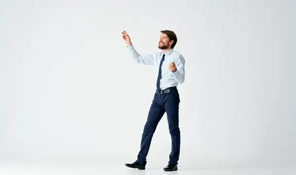 Бородатый мужчина в рубашке и галстуке жестикулирует на белом фоне