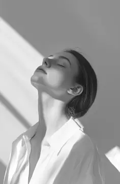 Молодая женщина с закрытыми глазами поднимает лицо к свету