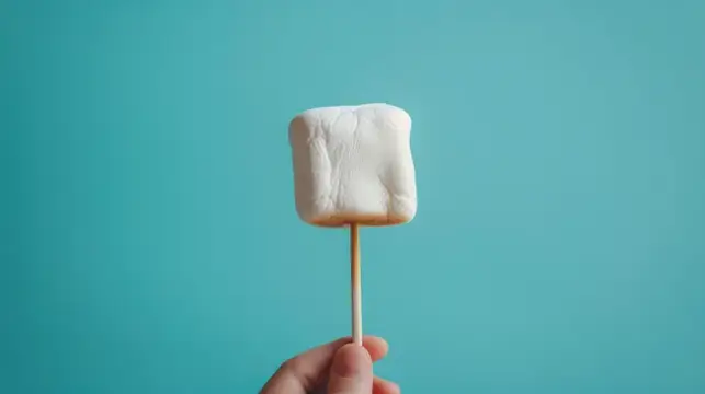 Рука держит зефир на шпажке на бирюзовом фоне