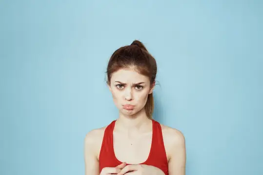 Молодая женщина с недовольным лицом надула губы на голубом фоне