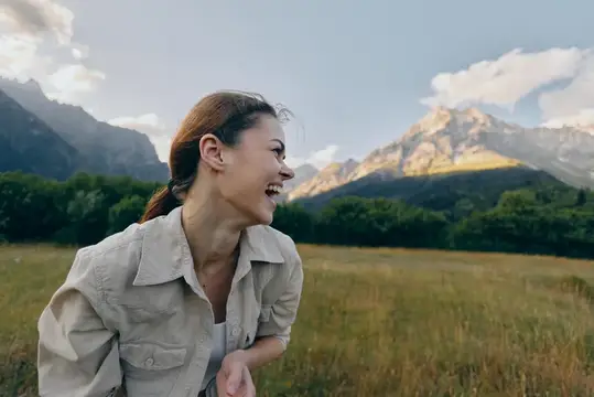Смеющаяся девушка на фоне гор и луга