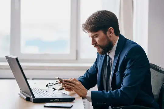 Мужчина сидит перед ноутбуком и работает, используя технологии