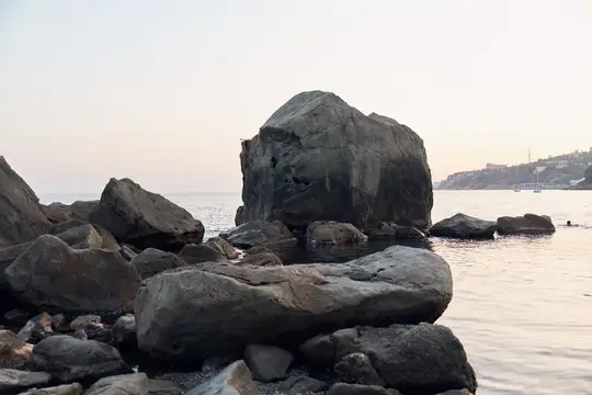 Большие тёмные камни на берегу моря в сумерках