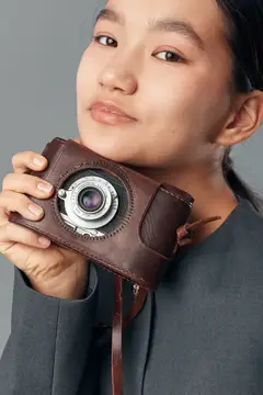 Портрет женщины со старомодным фотоаппаратом и кожаным чехлом, мягкий свет падает на лицо