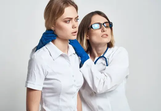 Врач в очках осматривает шею пациентки в белом халате