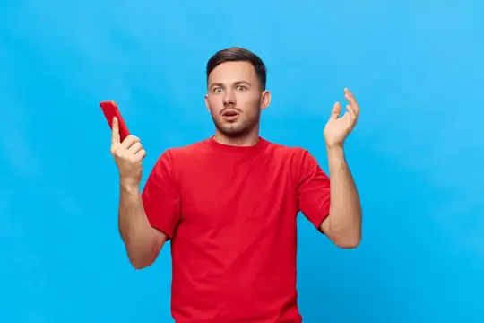 Удивлённый мужчина в красной футболке с телефоном на синем фоне