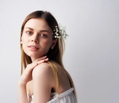 Молодая женщина с белыми цветами в волосах на светлом фоне
