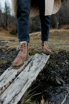 Ноги в рыжих ботинках на старой доске среди осеннего леса