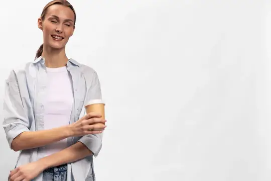 Улыбающаяся девушка с бумажным стаканом кофе на белом фоне