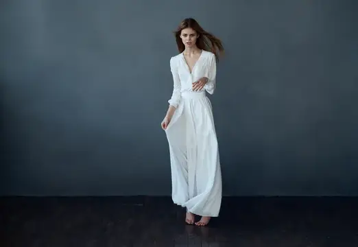 Молодая женщина в белом платье танцует на тёмном фоне
