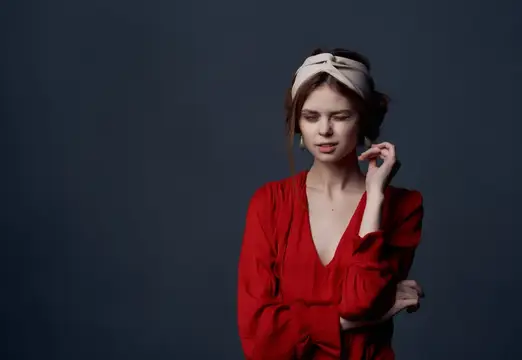 Привлекательная женщина в красном платье на роскошной вечеринке на тёмном фоне
