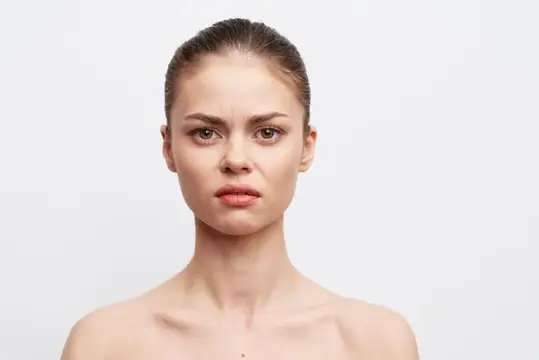 Молодая женщина с недовольным выражением лица на белом фоне