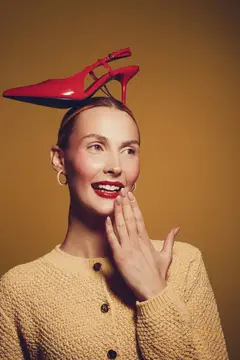 Улыбающаяся женщина с красной туфлей на голове