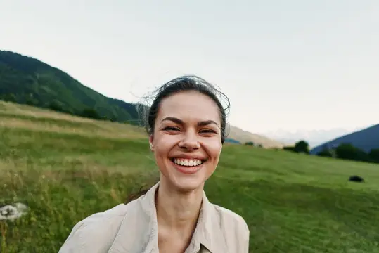 Улыбающаяся темноволосая женщина на фоне зелёных гор