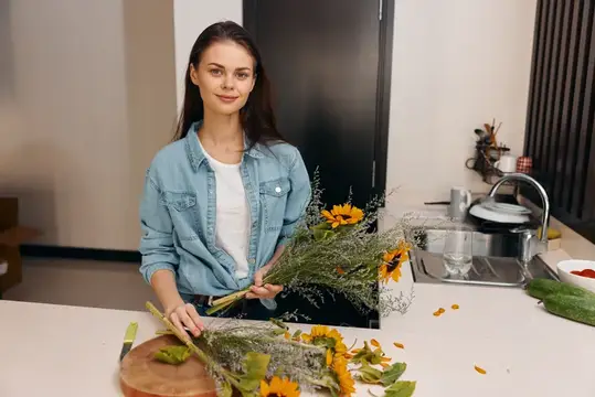 Улыбающаяся девушка с букетом подсолнухов на светлой кухне