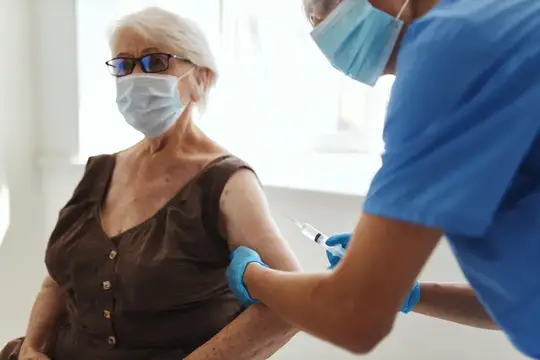 Пожилая женщина-пациентка получает вакцинацию в больнице, что подчеркивает безопасность иммунизации