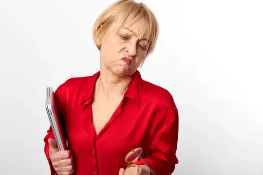Недовольная блондинка в красной рубашке с ноутбуком и очками