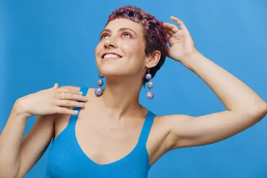 Улыбающаяся женщина с фиолетовыми кудрями на синем фоне