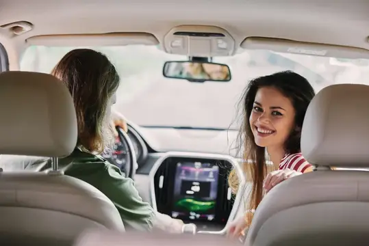 Улыбающаяся темноволосая девушка на пассажирском сиденье автомобиля