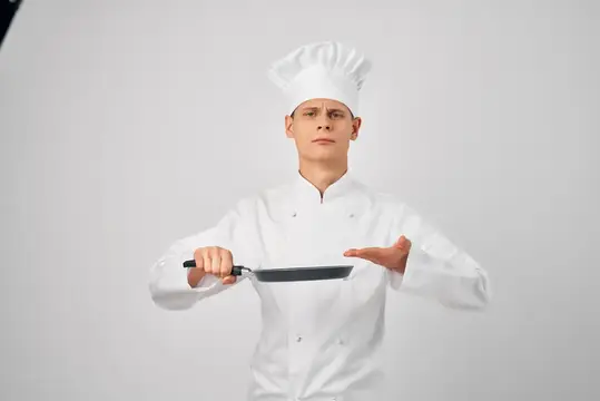 Повар с кухонной утварью, сковородой, работа по приготовлению пищи