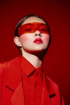 Азиатская девушка в красных очках и костюме на красном фоне