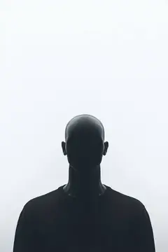 Силуэт лысого мужчины на фоне белого неба