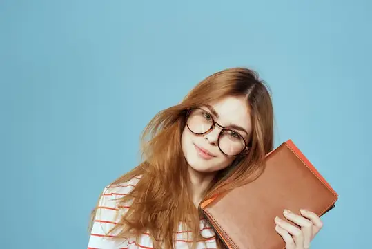 Рыжеволосая девушка в очках с блокнотом на голубом фоне