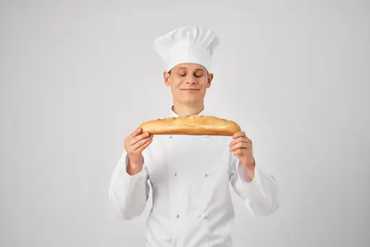 Повар-мужчина держит в руках багет, свежий продукт, профессиональная работа