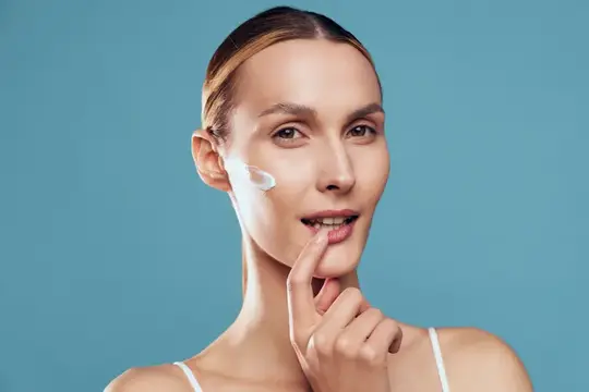 Женщина, красота, уход за кожей, нанесение крема для лица, крупный план портрет со спа-атмосферой