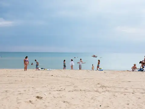 Люди отдыхают на песчаном пляже у моря в пасмурный день