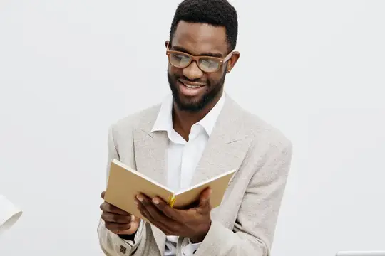 Улыбающийся темнокожий мужчина в очках читает книгу