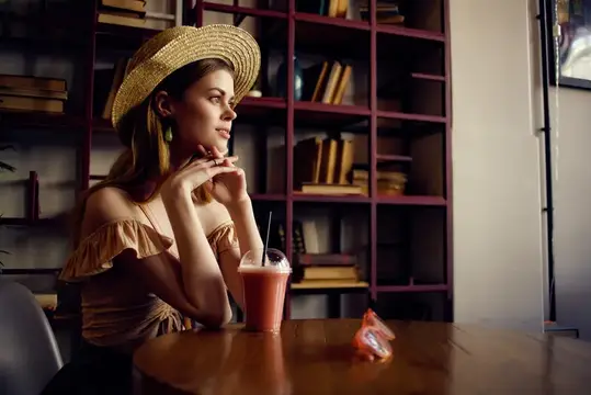 Жизнерадостная женщина с книгой в руках в кафе, стильная