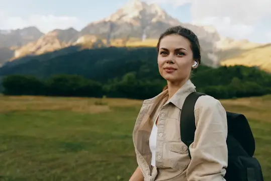 Молодая женщина с рюкзаком на фоне горных вершин