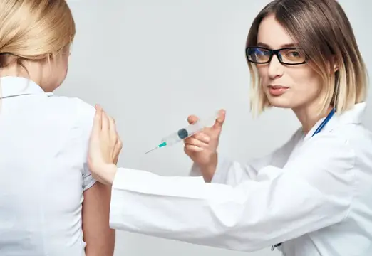 Женщина-врач в медицинском халате делает инъекцию пациенту