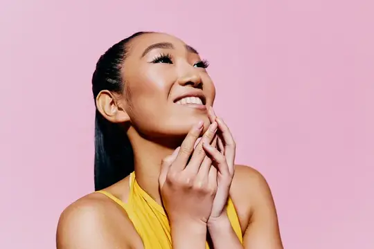 Улыбающаяся азиатская девушка с макияжем на розовом фоне