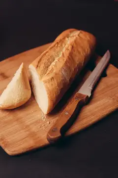 Нарезанный багет с ножом на деревянной доске
