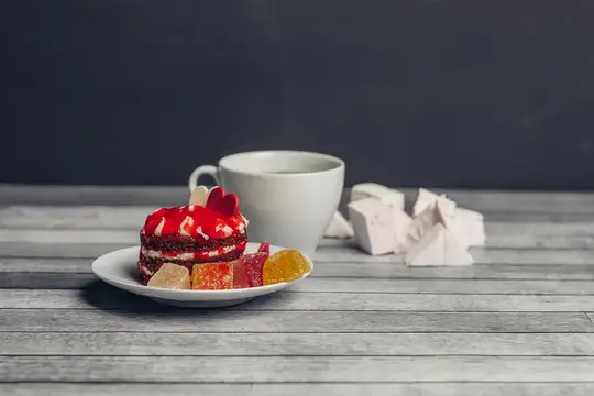 Пирожное с мармеладом и чашка чая на сером столе