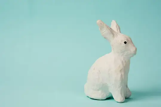 Праздничная игрушка — белый кролик на голубом фоне с пастельными цветами