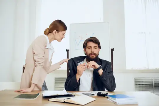 Женщина-руководитель отчитывает бородатого сотрудника в офисе