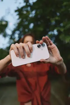 Девушка в красном платье фотографирует на смартфон в парке