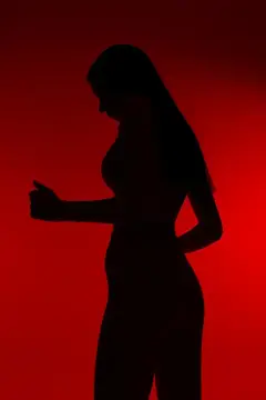 Темный силуэт спортивной женщины-бегуньи, запечатленной в движении на фоне интенсивного красного фона, подчеркивающий динамику, силу и спортивную решимость