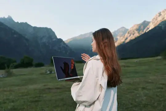 Девушка с ноутбуком на фоне горных вершин